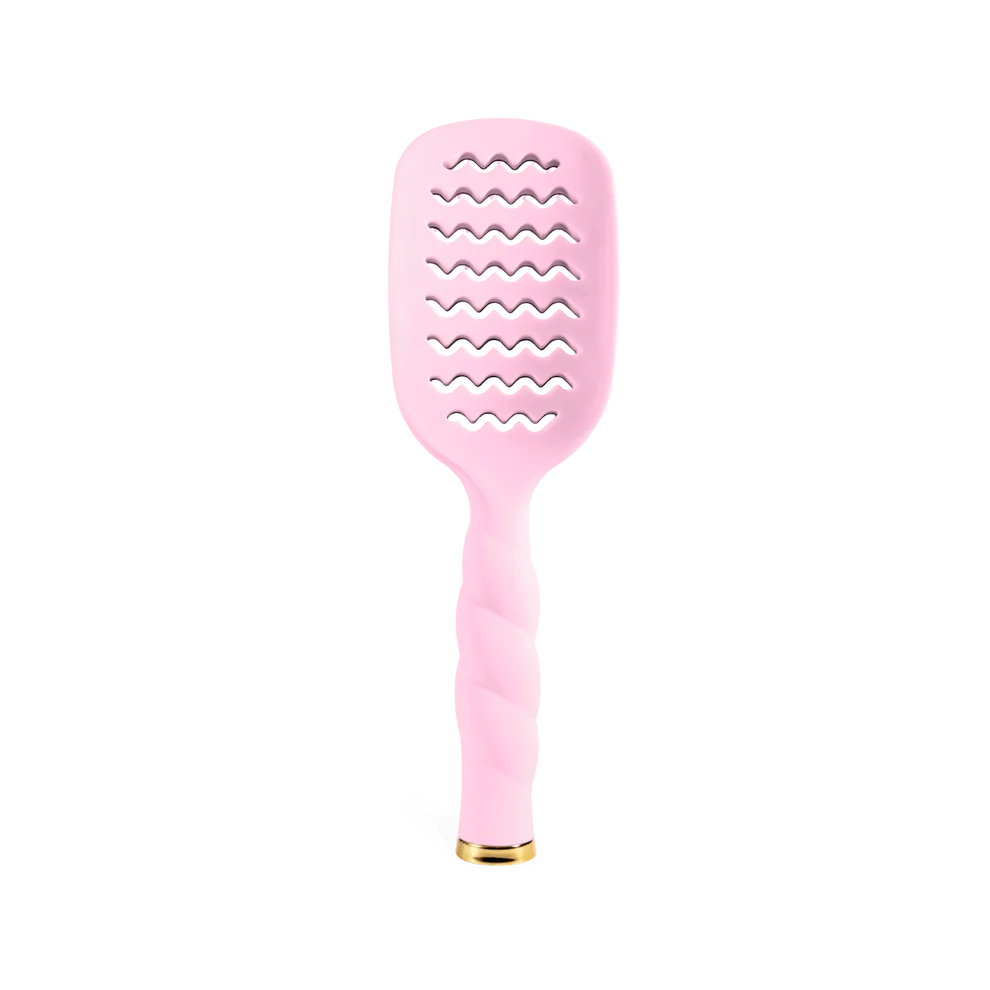 A light pink hairbrush with a wavy-toothed grooming head and a twisted handle, finished with a small gold accent at the base, shown on a plain white background.